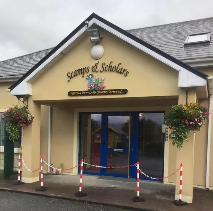 The front of Scamps & Scholars childcare centre on Langford Street, with hanging flower baskets either side of the blue doors